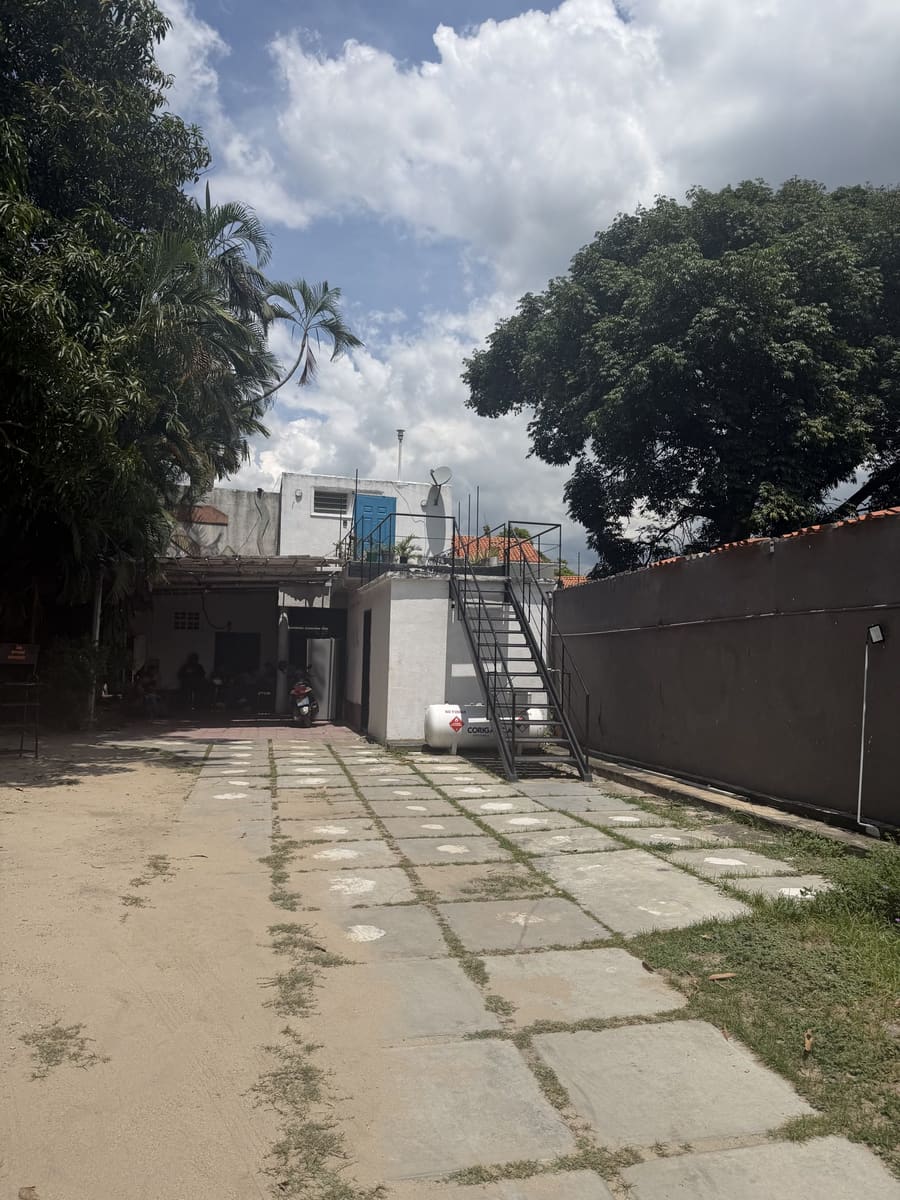 Entrada de Suela Limpia: un patio con una escalera que sube a la puerta azul